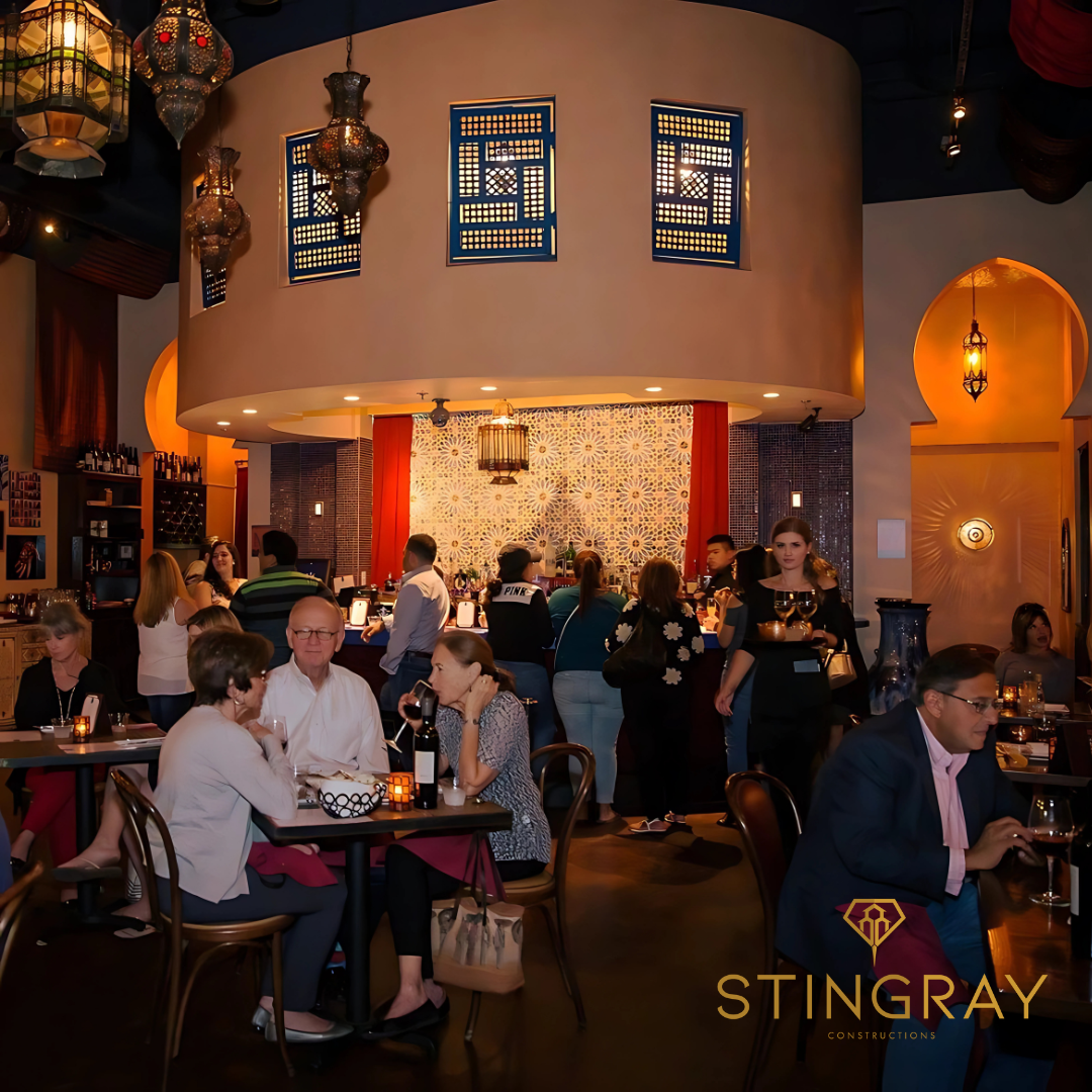 Guests dining inside Baboush restaurant with lantern lighting and mosaic bar in the background.