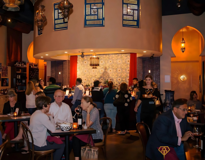 Guests dining inside Baboush restaurant with lantern lighting and mosaic bar in the background.
